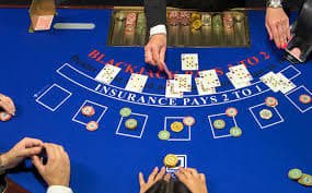 Meja kasino dengan dealer live yang melayani permainan kartu dan roulette dalam suasana elegan